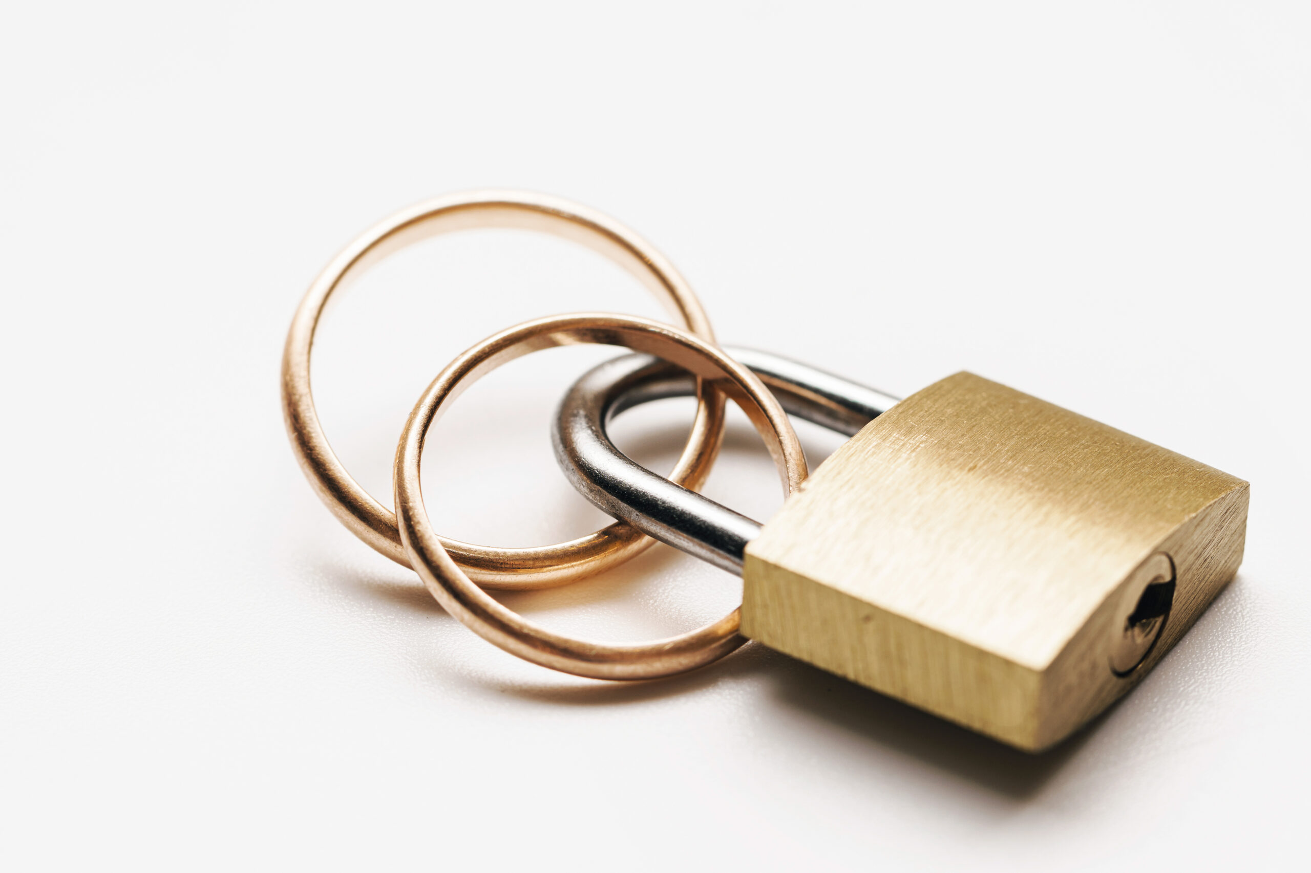 Observation : Pourquoi Macron porte-t-il deux alliances ? Two golden wedding rings locked on a metallic yellow padlock